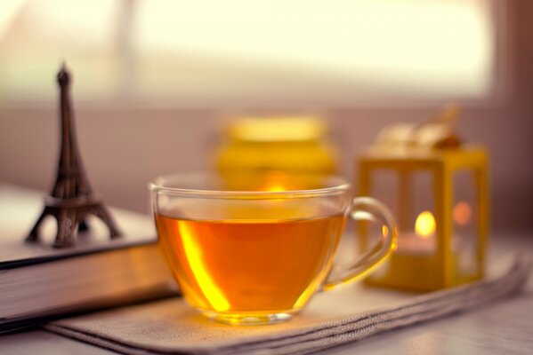 Reflection of the sun in a cup of tea and a statuette of the Eiffel Tower next to it