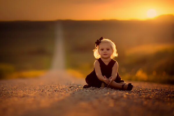 Beautiful young girl sitting on the road