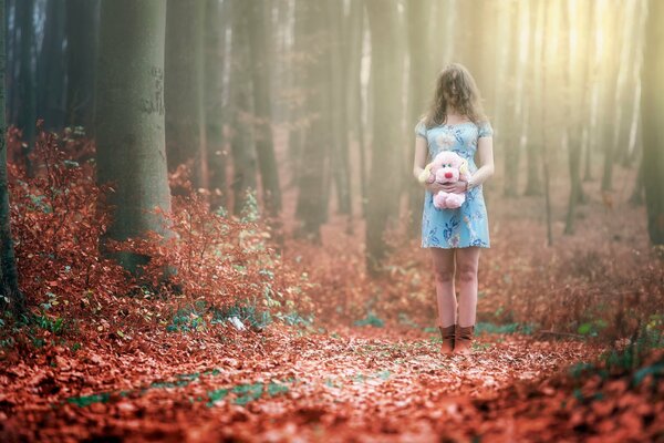 Chica con perro rosa de peluche en el bosque