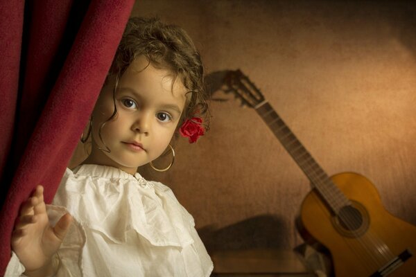 Beautiful curly-haired girl on the background of a guitar