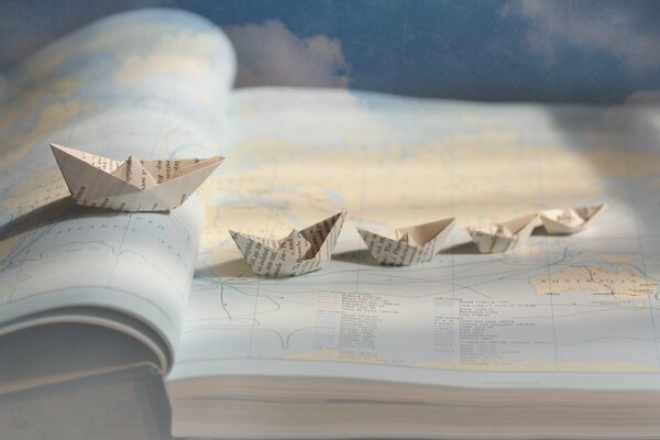 Origami of boats on a book with a world map