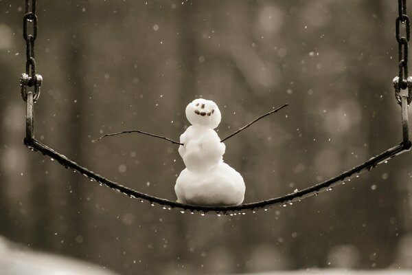 Fröhlicher kleiner Schneemann auf einer Schaukel