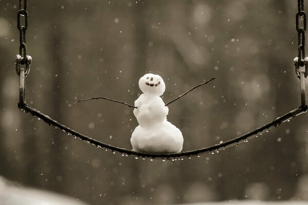 Pequeño muñeco de nieve alegre en un columpio