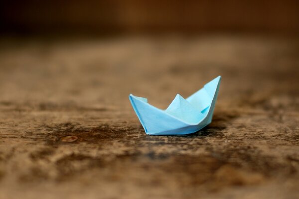 Origami of a blue boat on a wooden table