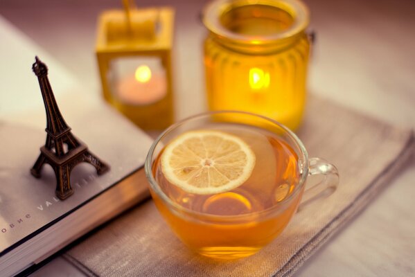 On the table there is a cup of tea with lemon Eiffel Tower and candles