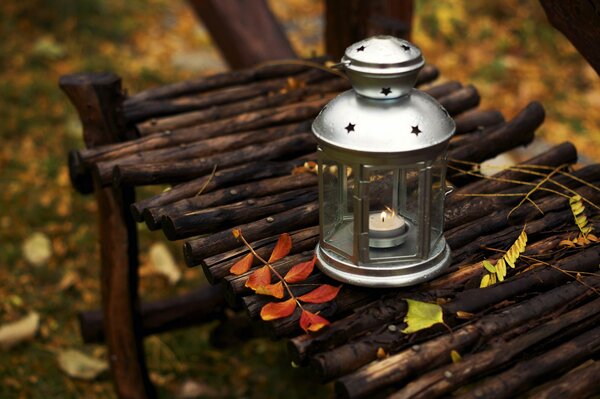 Lantern with a candle on a bench in autumn