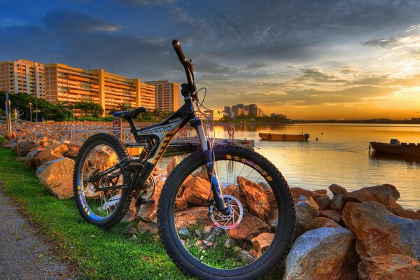 The bike stands on the riverbank against the sunset