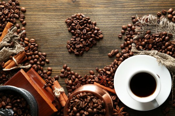 Coffee beans in the form of a heart next to a cup of coffee