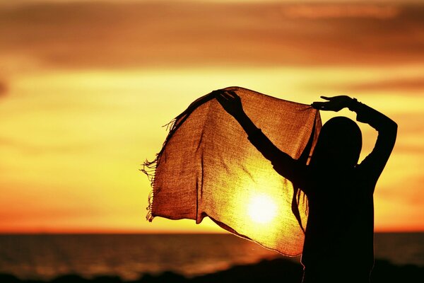 Fille chantante et paisible sur fond de coucher de soleil avec un mouchoir