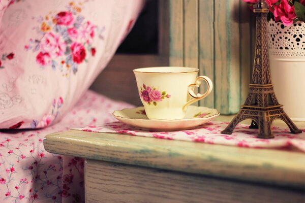 Provenza. la torre Eiffel en miniatura. par de té con flores en la cómoda. geranio rosa en maceta