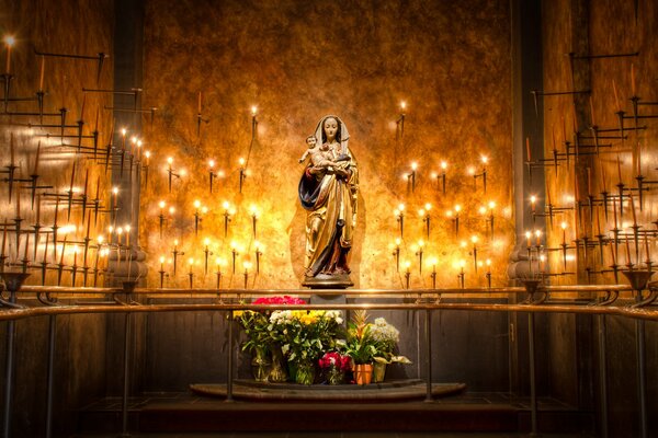 Estatua de la Virgen María con flores y velas