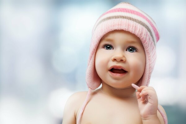 Il bambino in un berretto rosa guarda sorpreso