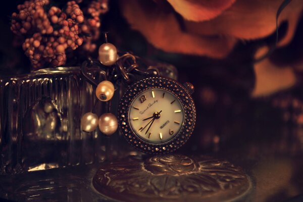 Beautiful metal watch with beads on a table with flowers