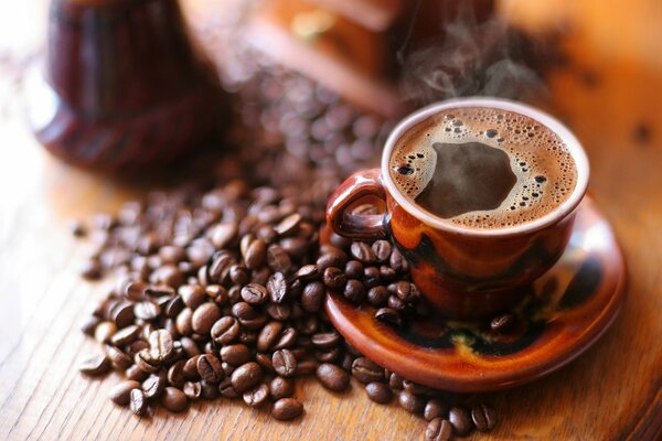 Café caliente con espuma en taza en platillo