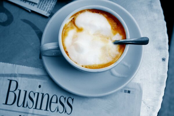 Кружка кофе со сливками на фоне газеты