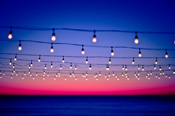 Líneas de alambre decoradas con lámparas en el fondo de la puesta de sol