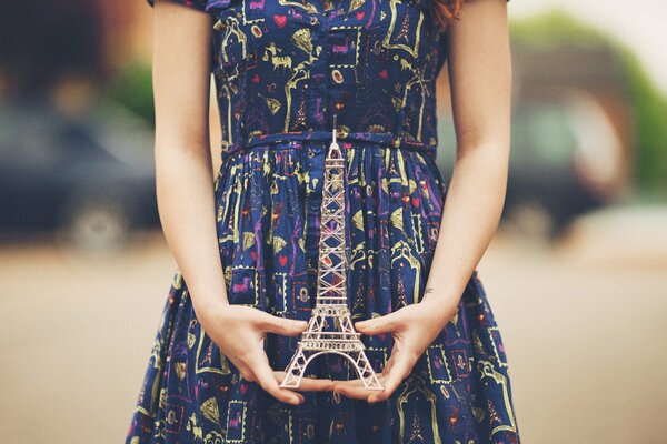 Una chica en sus manos sostiene una maqueta de la torre Eiffel