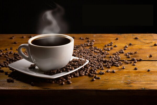 A cup of steaming coffee among coffee beans