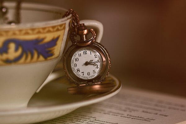 Tasse avec horloge de poche sur la table