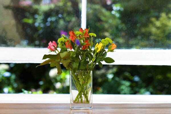 Bouquet di fiori sul davanzale della finestra sullo sfondo di una finestra con verde