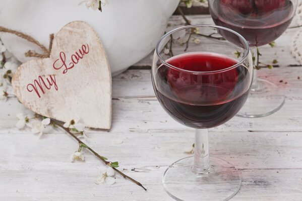 Bicchiere di vino rosso con cuore di legno sulla superficie di legno