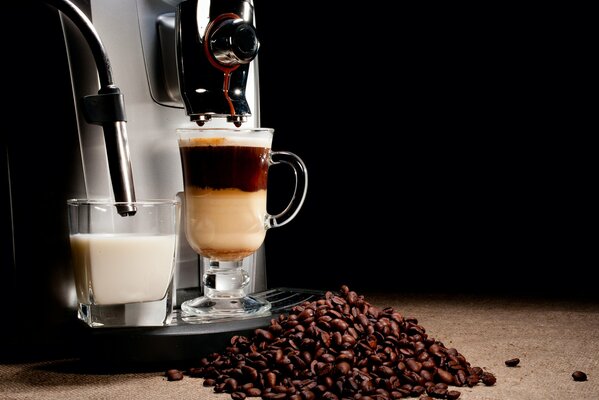 Kaffee und Milch in einer Kaffeemaschine auf schwarzem Hintergrund