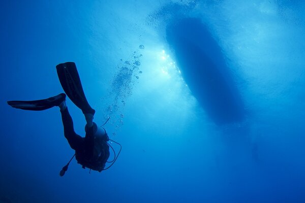 Taucher schwimmen tief unter einem Boot