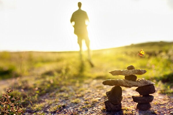 A house made of stones. A man running towards the sun