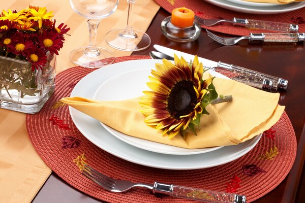 Una mesa con un plato en el que una servilleta y un girasol