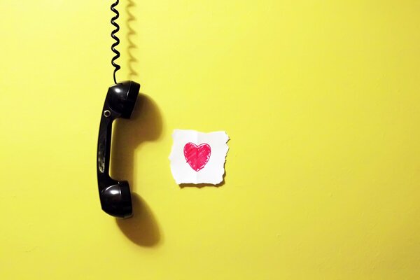 The handset is hanging on the background of a yellow wall