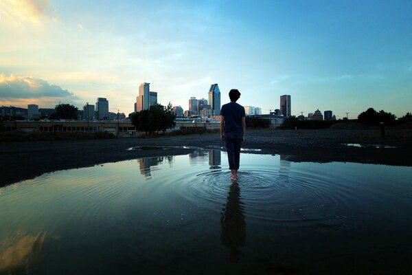 A man walks on the water towards the city