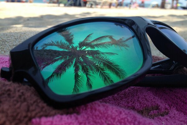 W okularach na plaży odbija się niebo i Palma