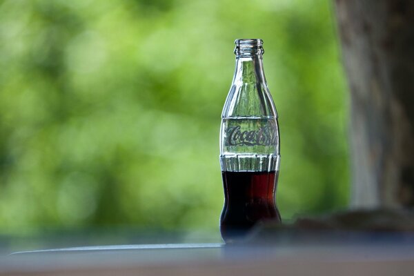 A drunk bottle of cola on a green background