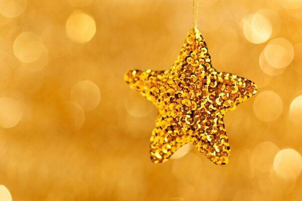 Złota błyszcząca świąteczna zabawka w kształcie gwiazdy