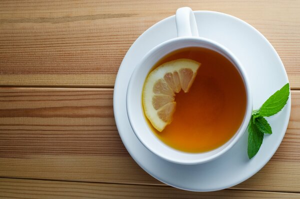 Tee mit Zitrone und Minze in einer weißen Tasse