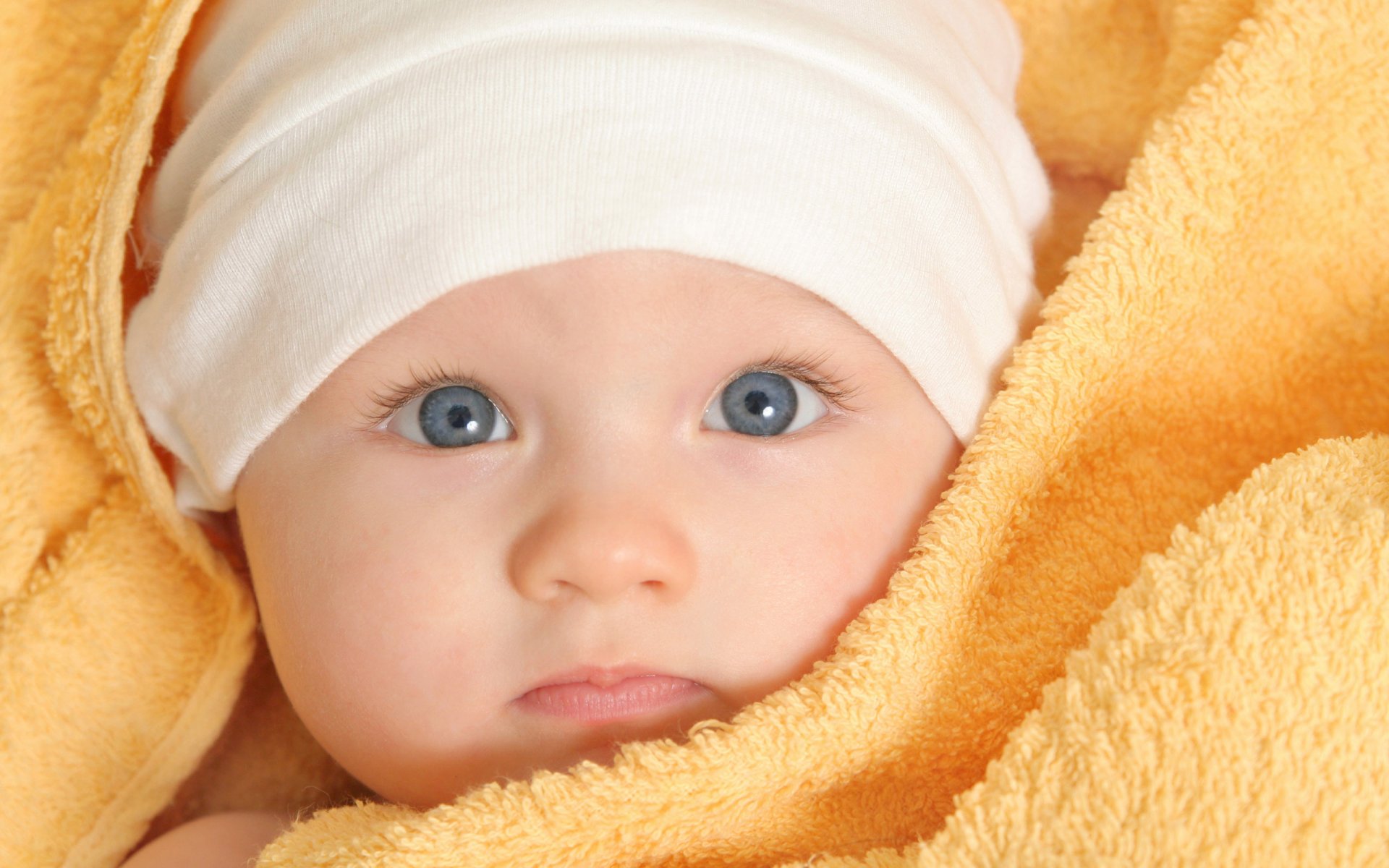 baby child baby baby boy girl yellow towel blue eyes white cap