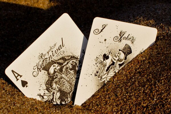 A picture of a playing card with a joker in the sand