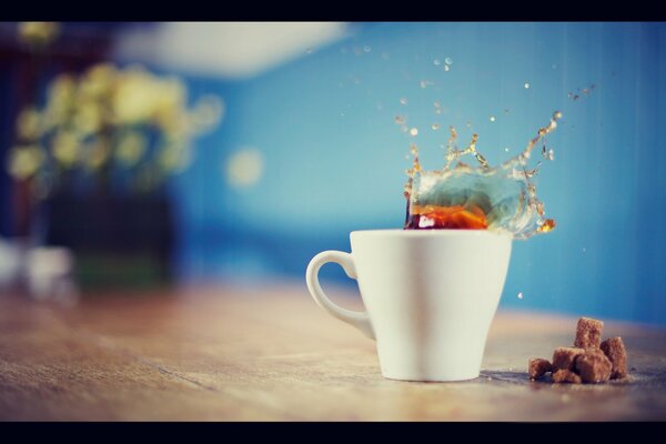 Splashes from falling sugar into a mug of tea