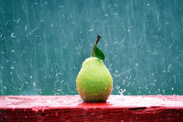 Poire sur un banc rouge sous la pluie