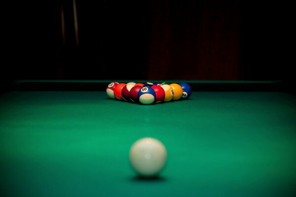 A white ball looking at the others on the background of a billiard table