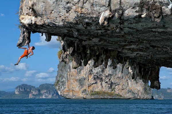 A climber hanging on a cliff above the sea