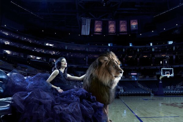 A girl in a dress and a lion in a basketball arena