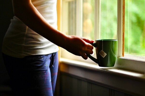She is standing at the window, a green cup of tea in her hand as always, and spring has come outside the window - green spring has come
