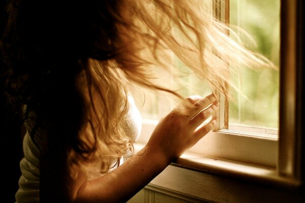 Fille cheveux ébouriffés regarde au loin par la fenêtre