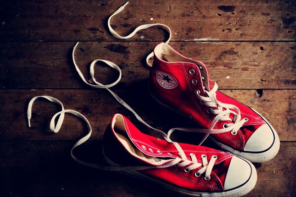 Red unlaced sneakers on the wooden floor