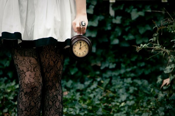 Imagen de una chica con un vestido blanco con un reloj en la mano