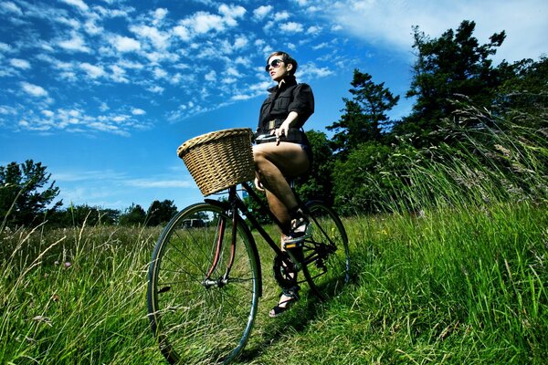 A girl with a basket on a bicycle in the forest edge