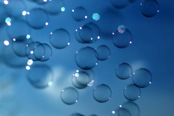 Bulles de savon avec des reflets au soleil. Fond bleu