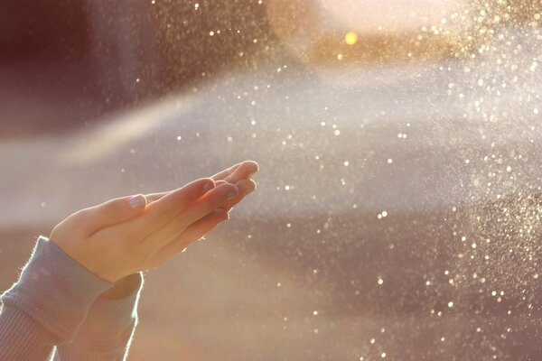 Spritzen Sie Wasser unter der Sonne und die Handflächen des Mädchens