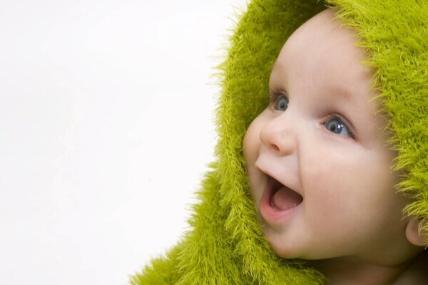 A child in a green hood smiles and